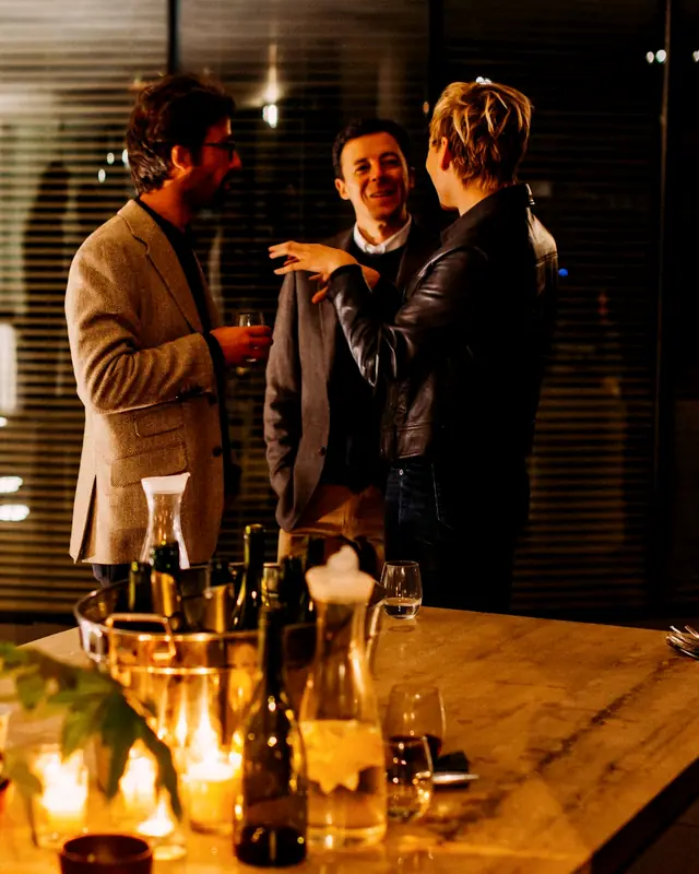 A group of men deep in conversation around a candlelit table
